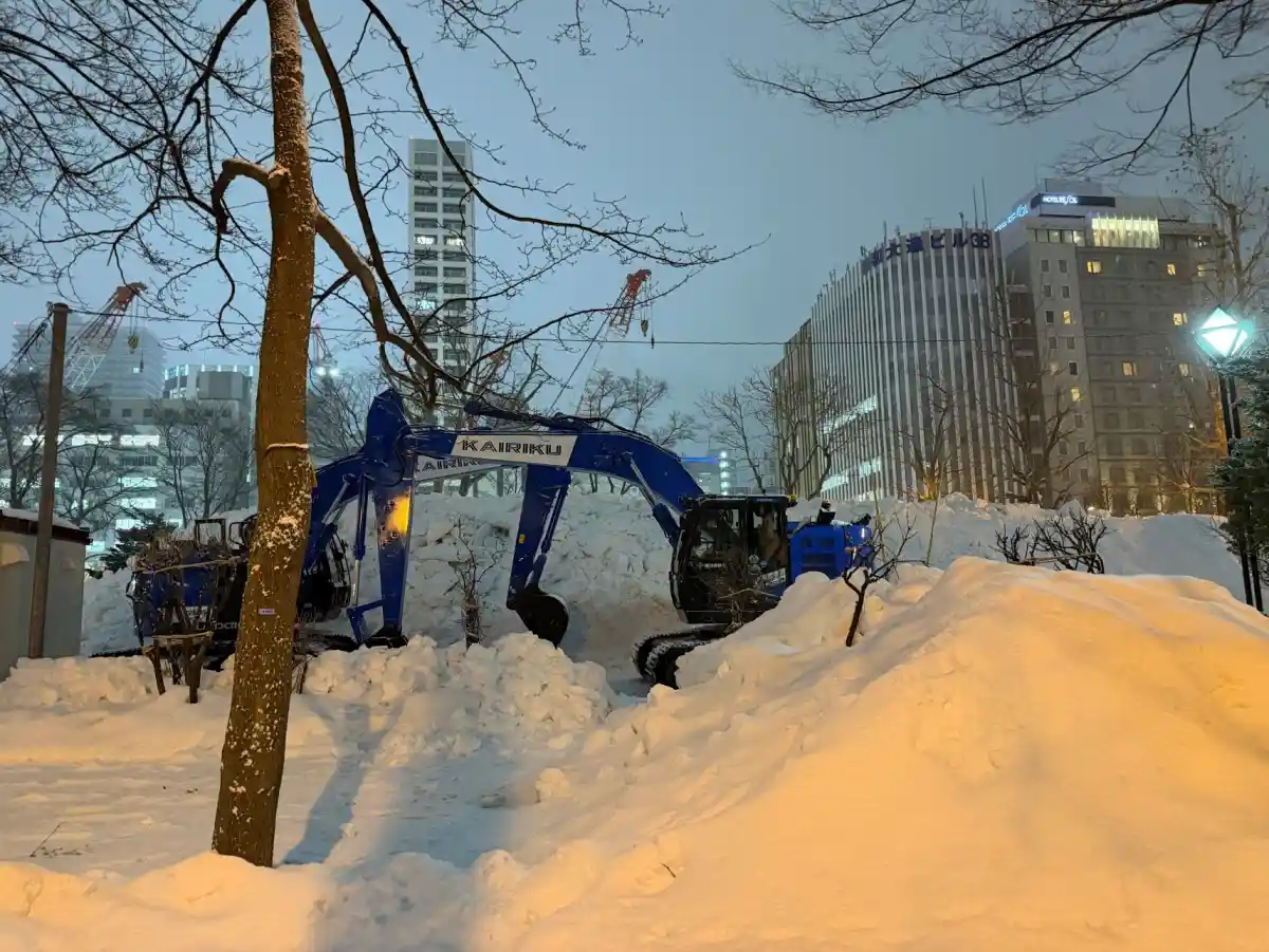 仕事を終えた青いショベルカーが、雪の山のそばで静かに佇んでいる。夜の大通公園